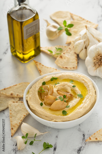 Roasted garlic hummus topped with olive oil and garlic cloves photo