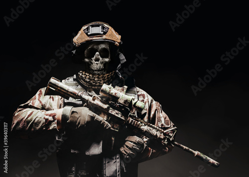 Konstfotografi Photo of a fully equipped skeleton zombie soldier standing in armored vest and holding rifle on black background