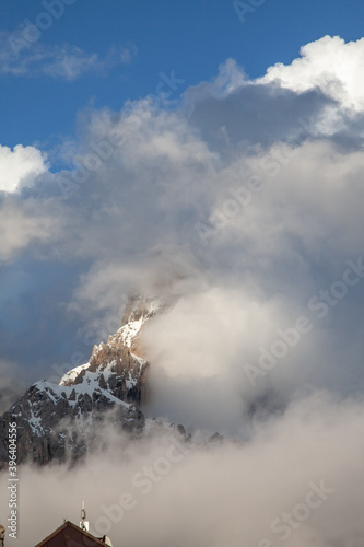 The mountain peaks of the Alps are shrouded in thick clouds. Evening light.