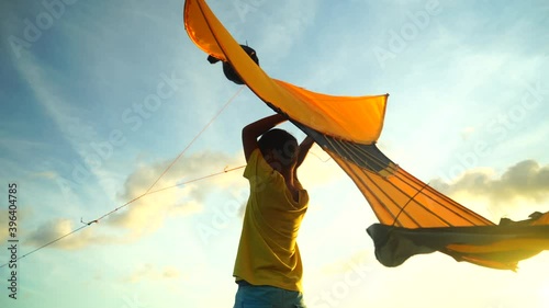 children playing kites in silhouettes having fun at sunset beach

