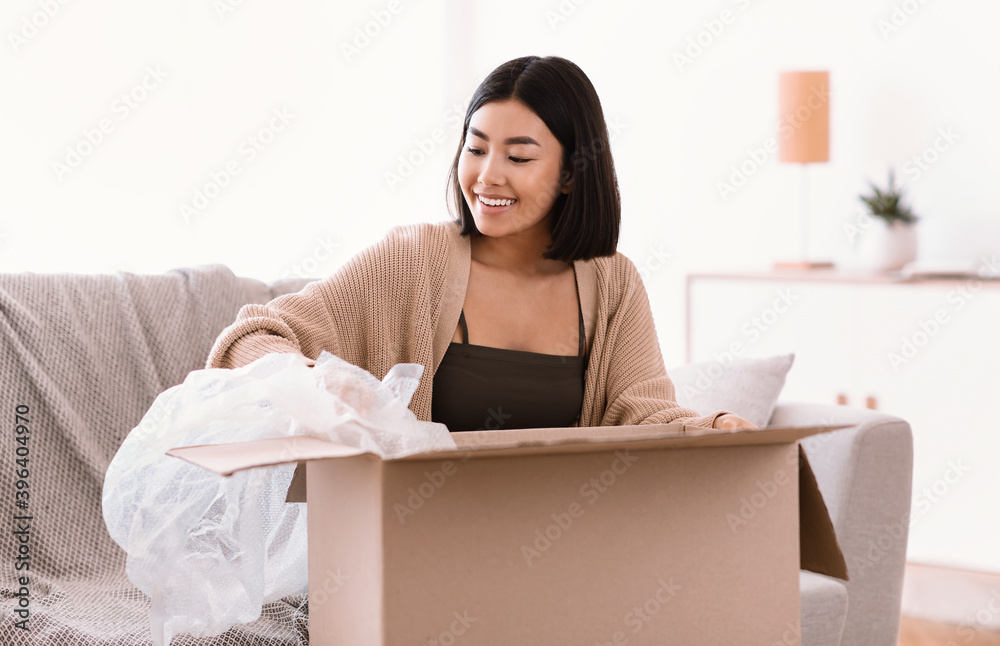 Smiling asian woman unpacking parcel after online shopping Smiling asian woman unpacking parcel after online shopping