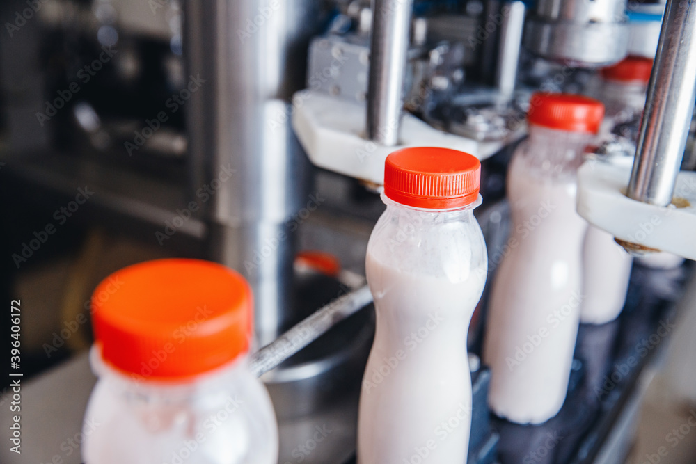 Dairy production, bottle of yoghurt on automated conveyor line, process of milk filling and packaging Dairy production, bottle of yoghurt on automated conveyor line, process of milk filling and packaging