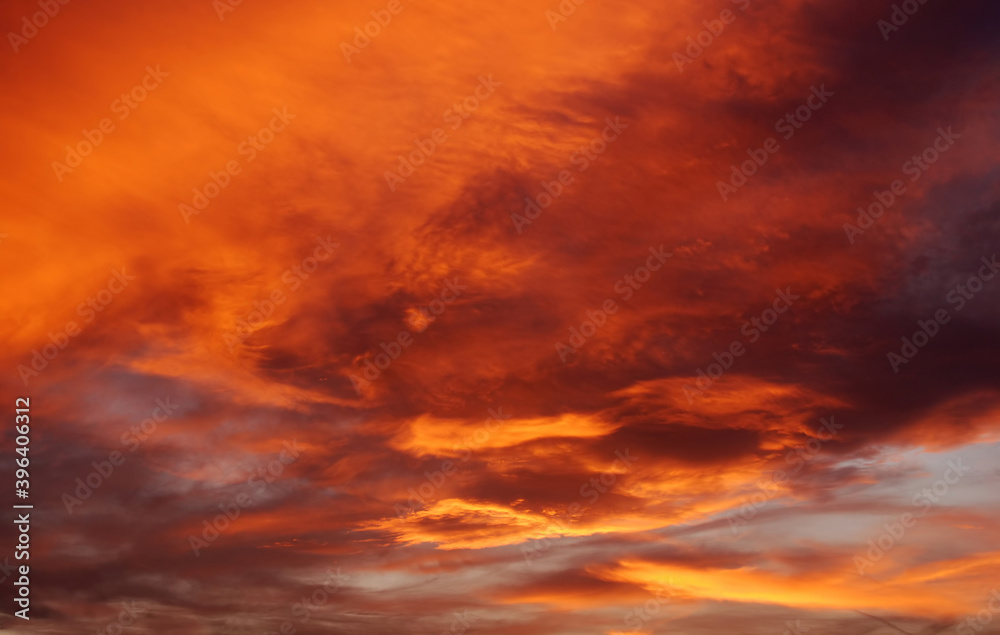 Dark blood red sky background. Dramatic heavy clouds with the hint of the sun at sunset. Many orange tones and patterns of clouds