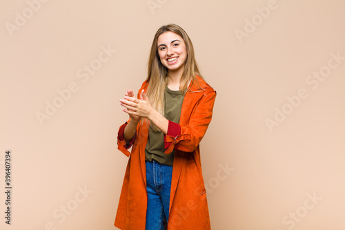 blonde woman feeling happy and successful, smiling and clapping hands, saying congratulations with an applause photo