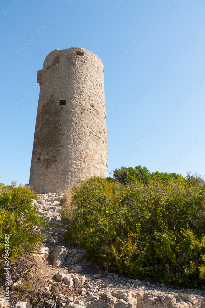 Medieval castle watchtower ruin. Torre Abadum or Badum tower. Beautiful protected Serra d'Irta Natural Park, Peniscola, Castellon province, Spain. Vertical shot.