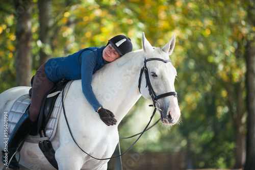 Equestrian lady hugging white horse neck