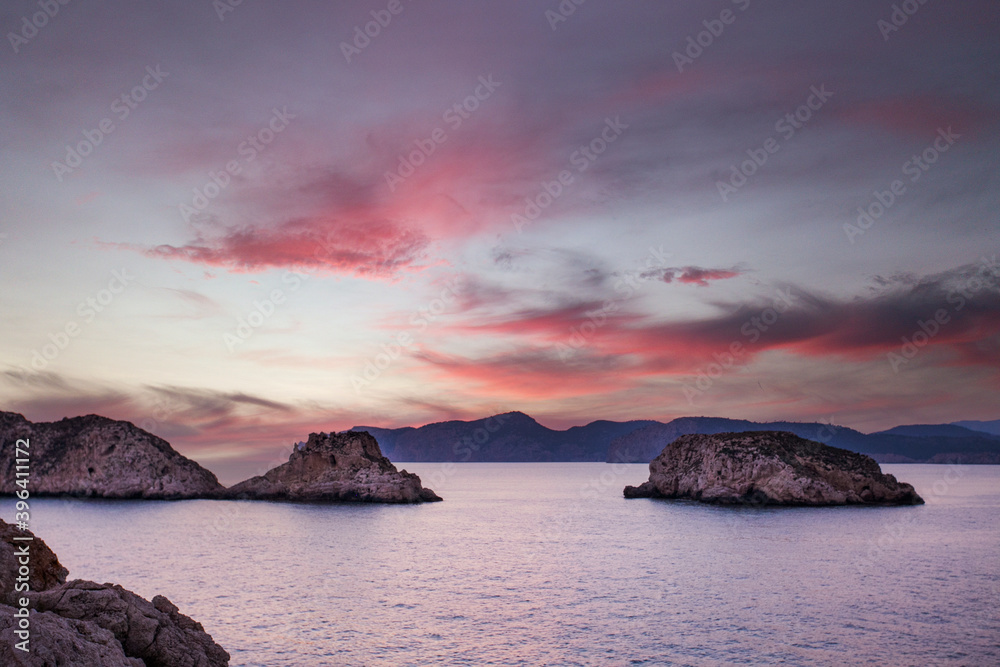 Puesta de sol con nubes rojizas en la pequeñas islas rocosas que se asientan en el mar