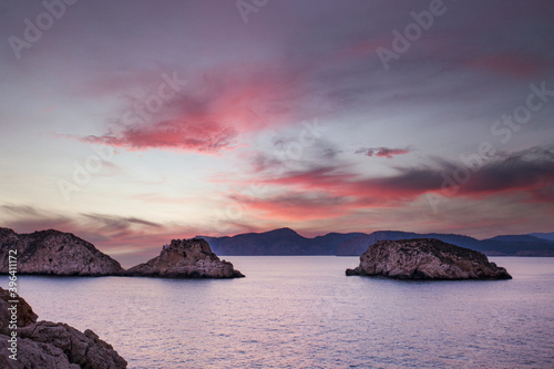 Puesta de sol con nubes rojizas en la pequeñas islas rocosas que se asientan en el mar photo