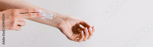 cropped view of woman with hand cream on arm isolated on grey, 