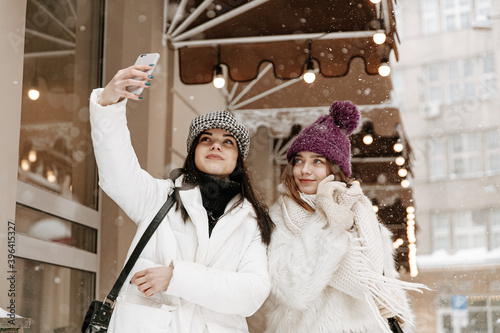 Pleasant ladies using mobile for doing selfie on street