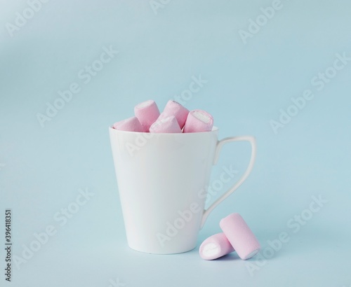 pink marshmallow in white cup on blue background. Christmas, mother's day, birthday card concept