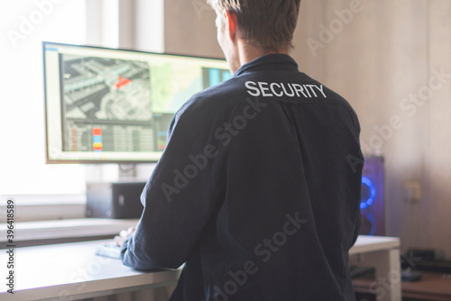 back view of male security sit in front of computer and check cctv camera online