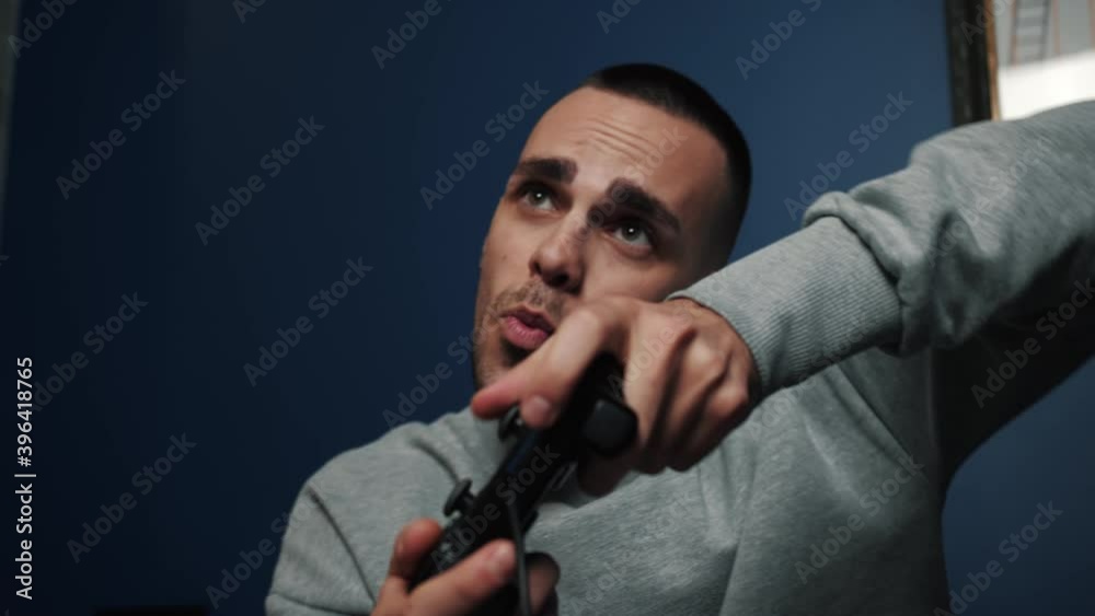 Excited young caucasian man gamer holding joystick controller playing video games sitting on the sofa at home. Excited young caucasian man gamer holding joystick controller playing video games sitting on the sofa at home.