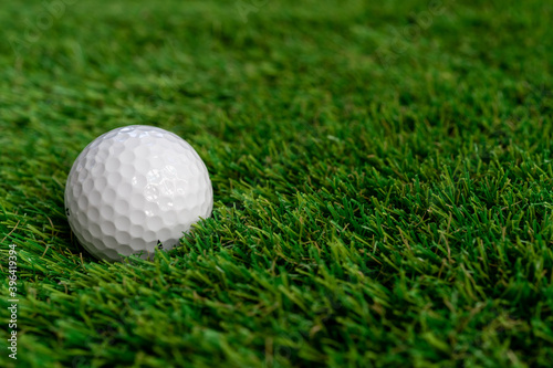 Golf ball on green artificial grass, top view with space for text - macro, selective focus, space for text