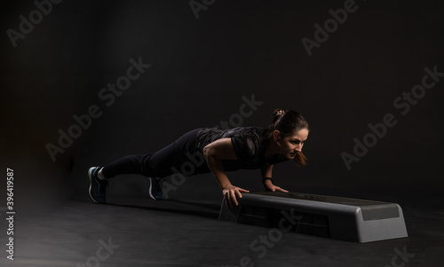 Fitness on the step platforms, pressed. Engaged in sports on a black background Smiling with a beautiful smile