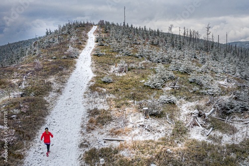 Drone view of a woman runner on a mountain trail in a red sweatshirt. Inspiration and motivation.