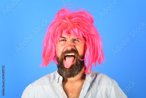 Bearded man portrait. Smiling bearded man. Smiling man shows tongue. Portrait of smiling man. Isolated. Wig. Colorfull hair. Emotions. Funny faces.