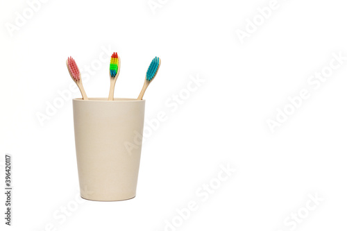 Pink, blue and rainbow bamboo toothbrush in a cup
