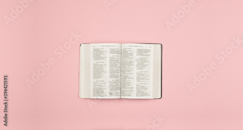 Open Bible book on the table. On a pink background
