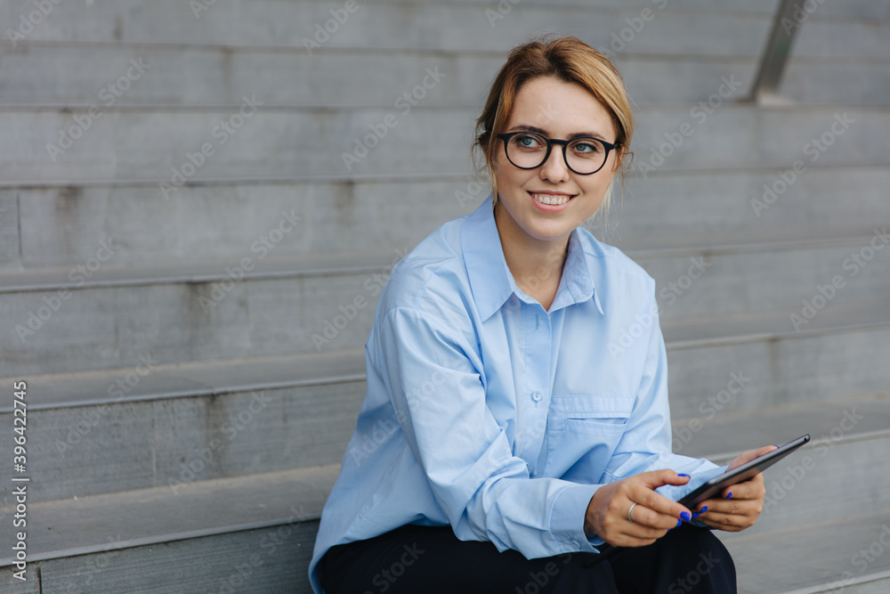 Smiling blonde working on tablet outdoors