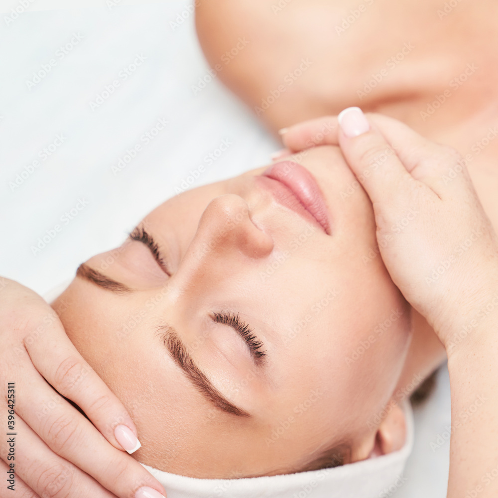 Face massage at spa salon. Doctor hands. Closeup view. High quality photo. Pretty female patient. Beauty treatment. Healthy skin procedure. Young woman head. Light background. Scrub rejuvenation.