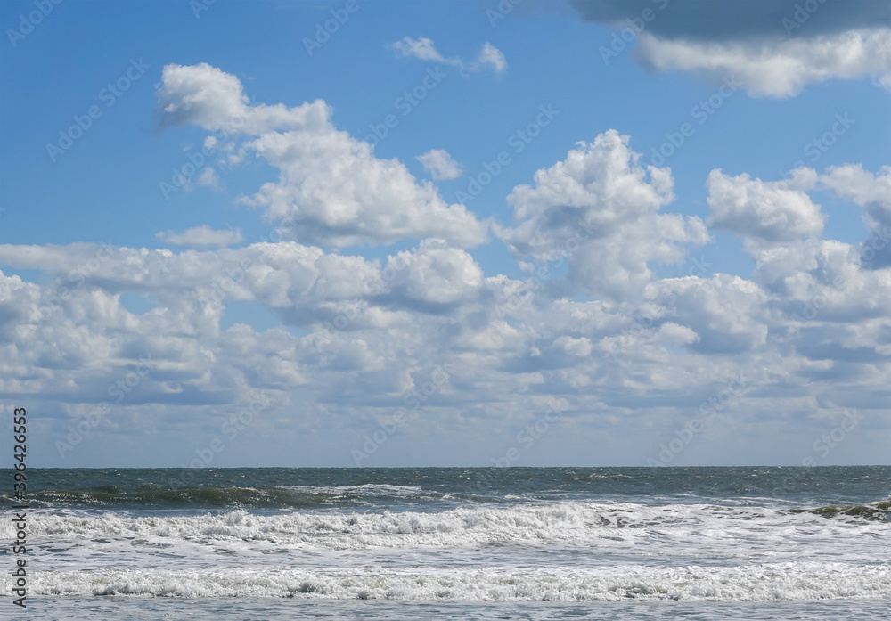 Beautiful white puffy cloudscape over a rough ocean with wild waves
