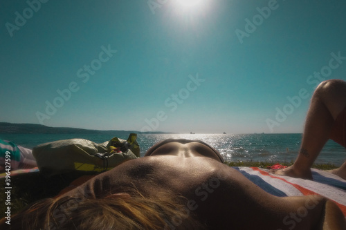 Back view of a woman sunbathing in front of a majestical ocean. Sexy photo of sunbathing with view of an ass. photo