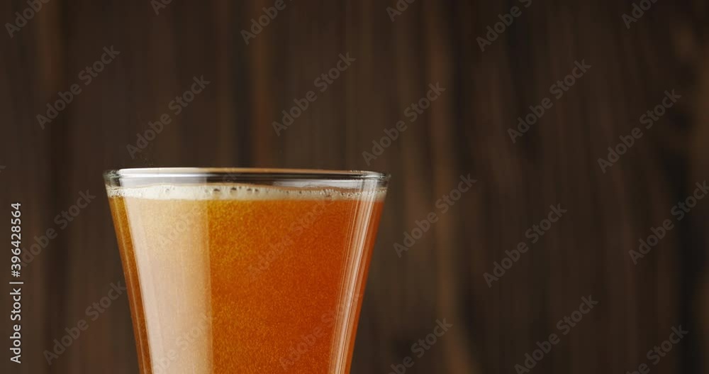Cold beer is slowly poured into a glass on a dark wooden background, there is a lot of foam and bubbles in the glass. Slow motion. Beer is pouring into a glass isolated on a wooden background. Cold beer is slowly poured into a glass on a dark wooden background, there is a lot of foam and bubbles in the glass. Slow motion. Beer is pouring into a glass isolated on a wooden background.