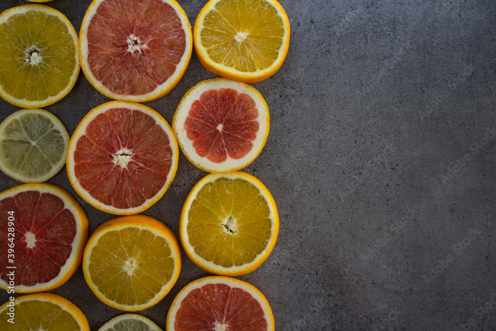 Fruit frame or border. Fresh juicy orange, lemon and grapefruit slices on a table. Dark gray background with copy space. Healthy eating concept.  