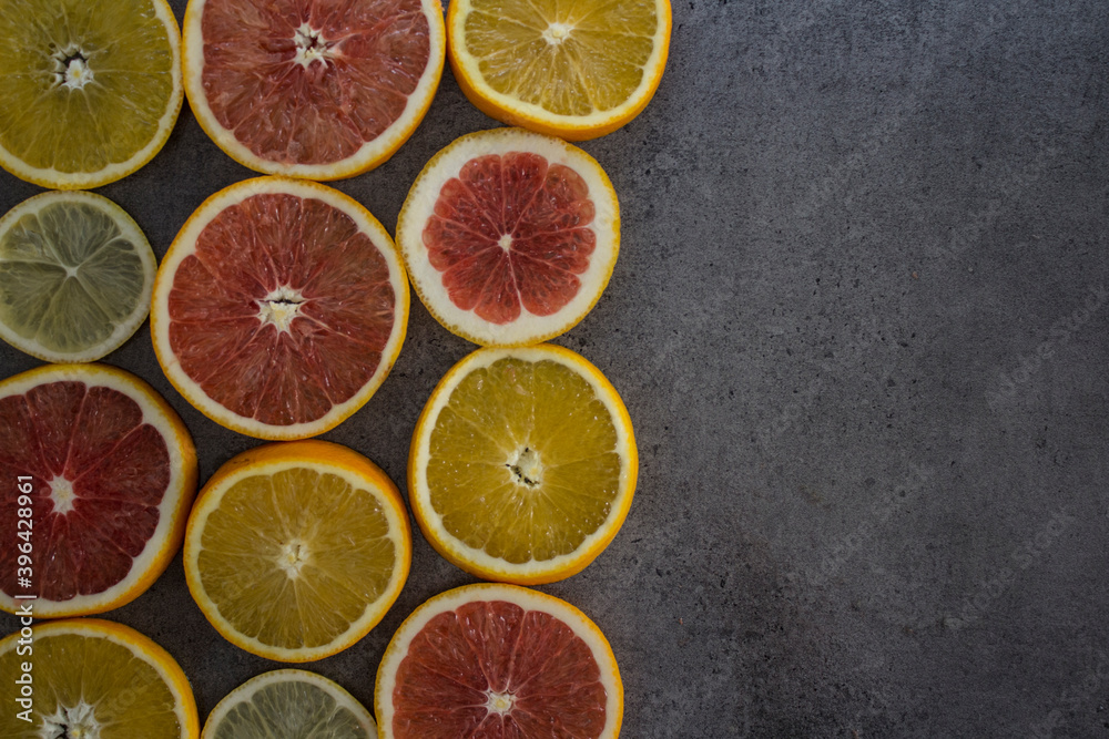 Fruit frame or border. Fresh juicy orange, lemon and grapefruit slices on a table. Dark gray background with copy space. Healthy eating concept. Fruit frame or border. Fresh juicy orange, lemon and grapefruit slices on a table. Dark gray background with copy space. Healthy eating concept.