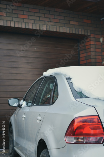 Detail of a car parked near the garage door in winter. Selective focus.