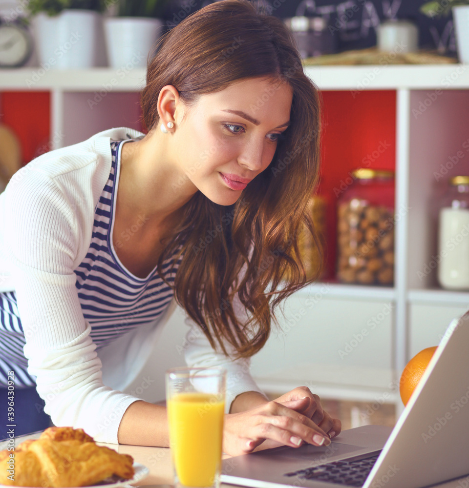Young woman sitting near desk in the kitchen Young woman sitting near desk in the kitchen