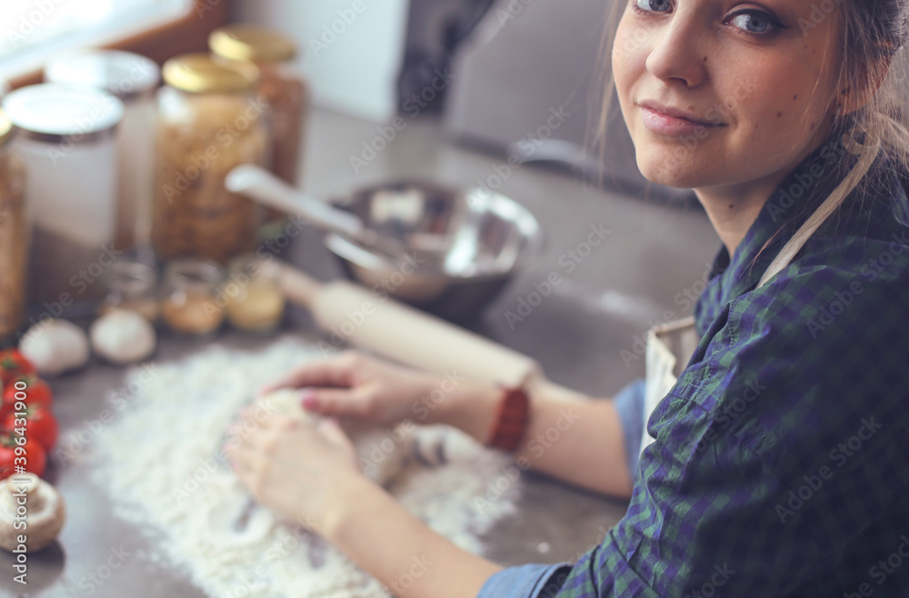 Young woman standing by the stove in the kitchen . Young woman standing by the stove in the kitchen .