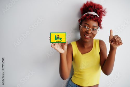 African woman with afro hair hold Ogun flag isolated on white background, show thumb up. States of Nigeria concept. photo