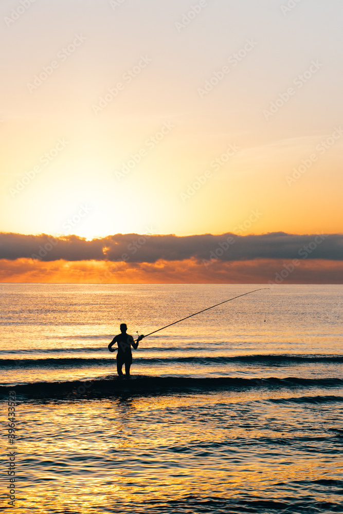 IMAGE OF A PERSON FISHING AT THE SEA DURING SUNRISE