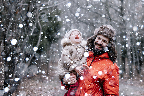 Happy loving family! Father and his baby are playing and hugging outdoors. Little child and daddy on snowy winter walk in nature. Concept of the first long-awaited winter snowfall