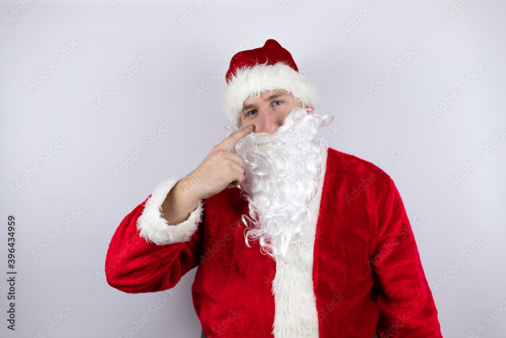 Man dressed as Santa Claus standing over isolated white background Pointing to the eye watching you gesture, suspicious expression Man dressed as Santa Claus standing over isolated white background Pointing to the eye watching you gesture, suspicious expression