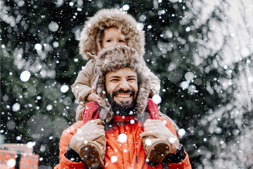 Happy loving family! Father and his baby are playing and hugging outdoors. Little child and daddy on snowy winter walk in nature. Concept of the first long-awaited winter snowfall