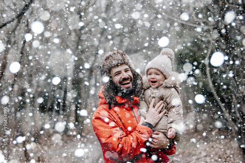 Happy loving family! Father and his baby are playing and hugging outdoors. Little child and daddy on snowy winter walk in nature. Concept of the first long-awaited winter snowfall