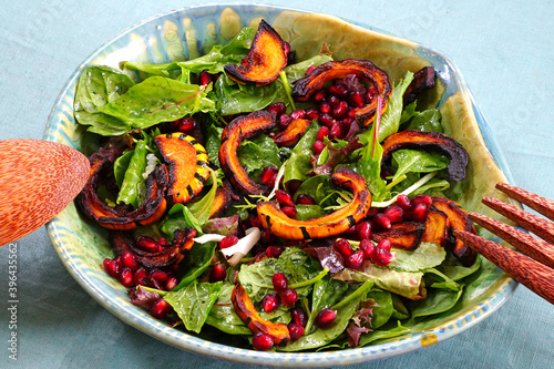 Salad greens with roasted delicata squash and pomegranate seeds photo