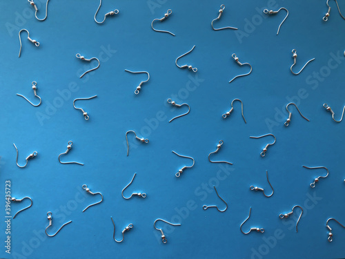 Fototapeta A pattern of earring hooks to create jewelry on a blue background