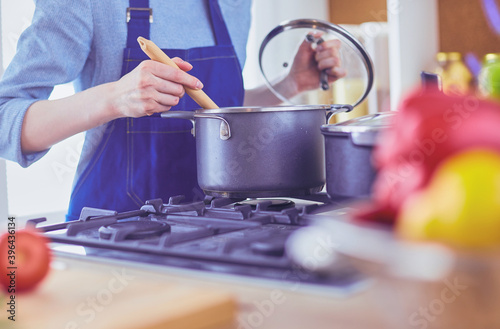 Cooking woman in kitchen with wooden spoon