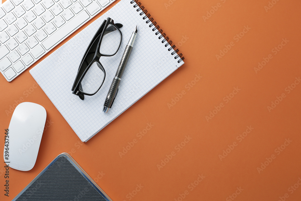 Glasses keyboard mouse pen notepad and diary on orange background Glasses keyboard mouse pen notepad and diary on orange background