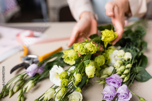 Partial view of florist making bouquet with Eustoma in flower shop on blurred background