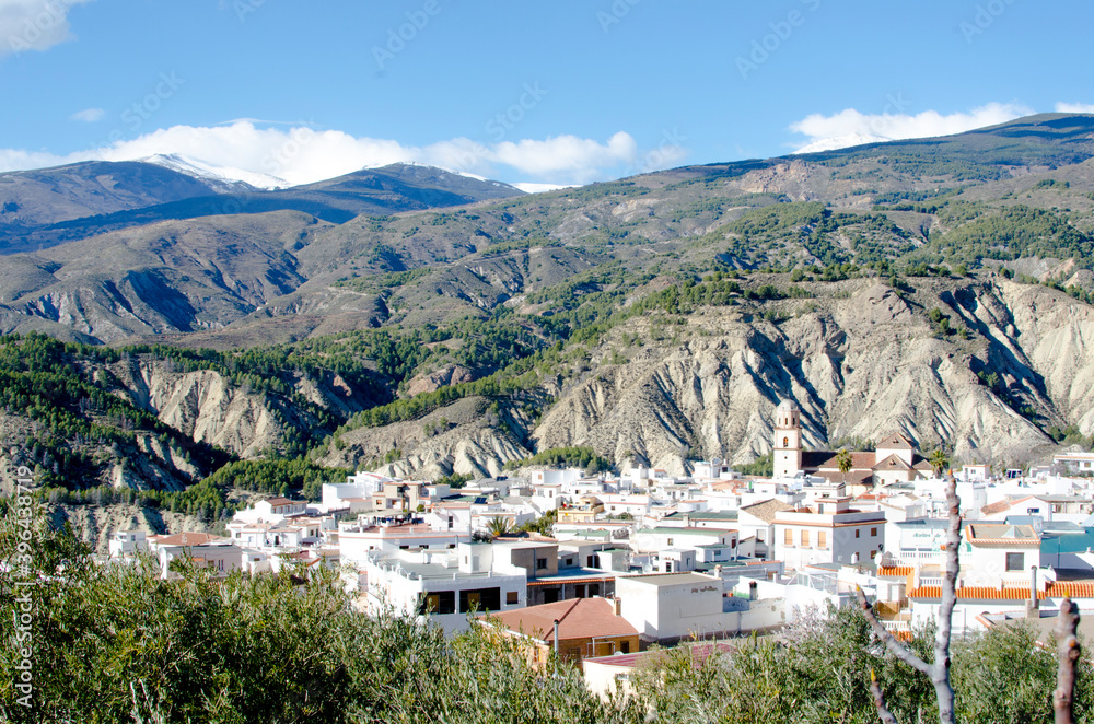 Alcolea, Alpujarra, Almeria, Andalusia, white mountain town in a valley between badlands, Sierra Nevada in the background
