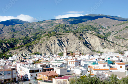 Alcolea, Alpujarra, Almeria, Andalusia, white mountain town in a valley between badlands, Sierra Nevada in the background © javiemebravo