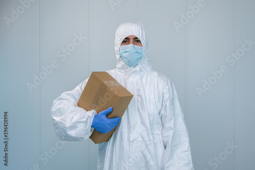 A male nurse in a protective suit PPE shows a box in the hospital. Coronavirus.