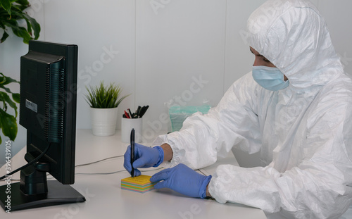 A nurse in a protective suit is handwriting a note. Coronavirus prevention.