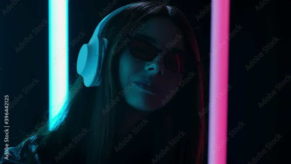 Portrait of a pretty young beautiful woman in sunglasses listening music with big white headphones, dancing and chews gum. Close up. Slow motion. Portrait of a pretty young beautiful woman in sunglasses listening music with big white headphones, dancing and chews gum. Close up. Slow motion.