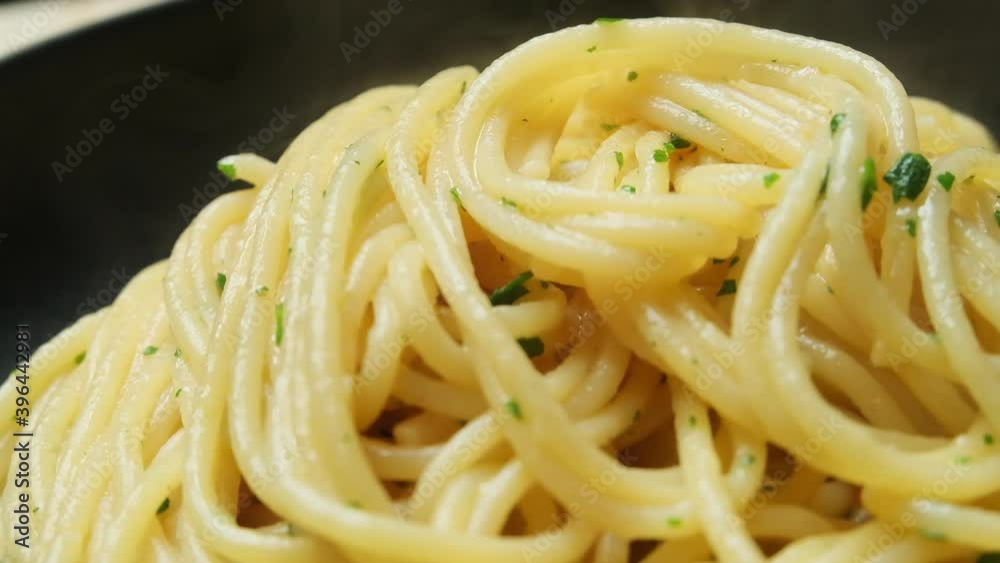 Spaghetti in the kitchen of an Italian chef elegant serving. Delicious spaghetti pasta with olive oil in a black plate. slow video rotation Spaghetti in the kitchen of an Italian chef elegant serving. Delicious spaghetti pasta with olive oil in a black plate. slow video rotation